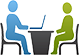 two people sitting at a table, one has a laptop